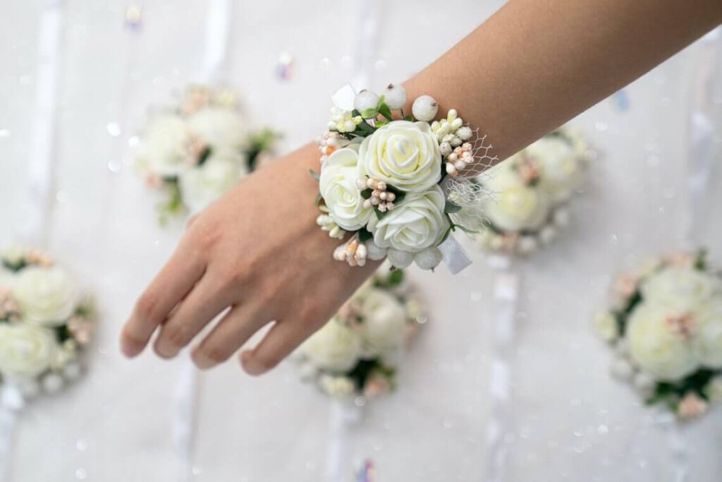 De bruid draagt een polscorsage van witte bloemen als alternatief voor een bruidsboeket. 