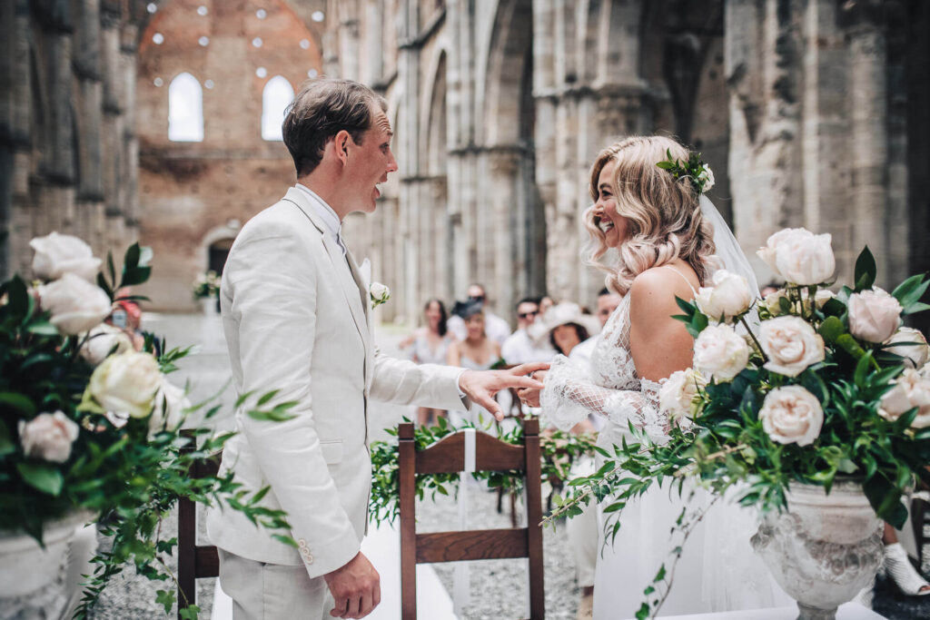 Ceremonieboekje kerkelijk huwelijk: bruidspaar in witte trouwkledij wisselt de trouwringen uit. 