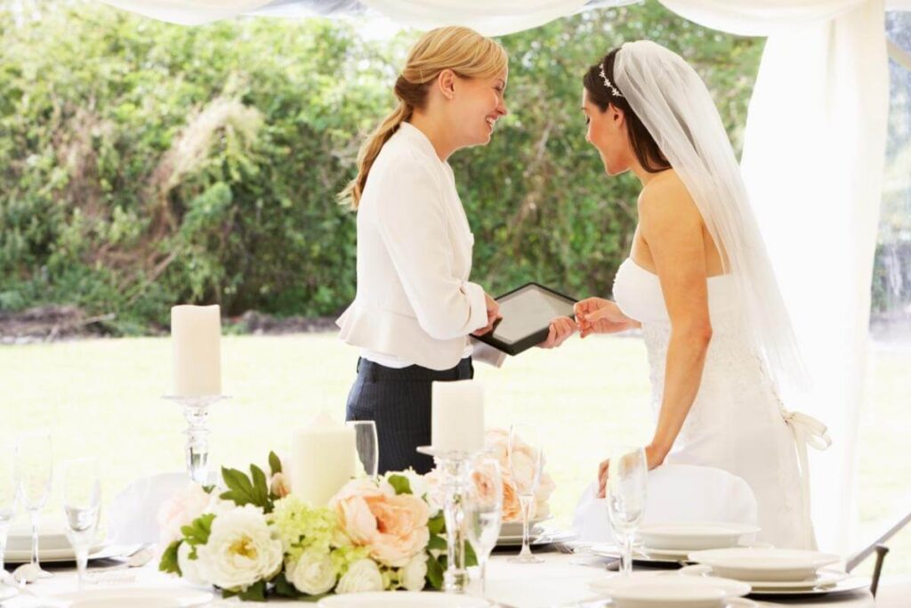 Hoe begin je aan een huwelijk met een wedding planner? Bruid en wedding planner overleggen aan feesttafel.