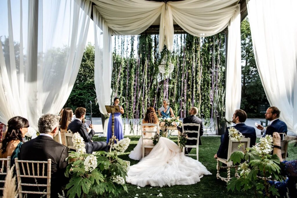 Bruidspaar tijdens huwelijksceremonie in een tent en met paarse accenten. 