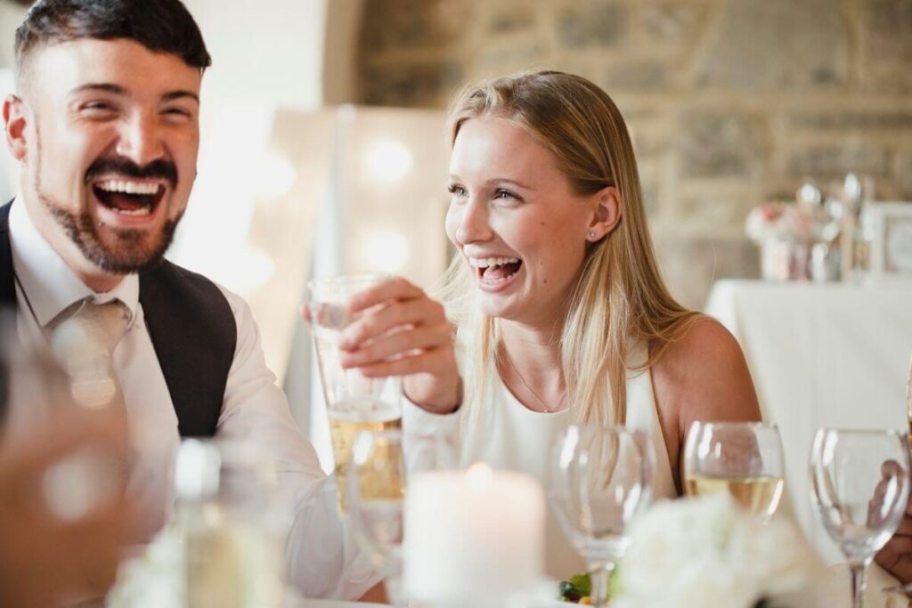 Gasten bezighouden op bruiloft: de huwelijksgasten zitten aan tafel en lachen met de trouwquiz. 