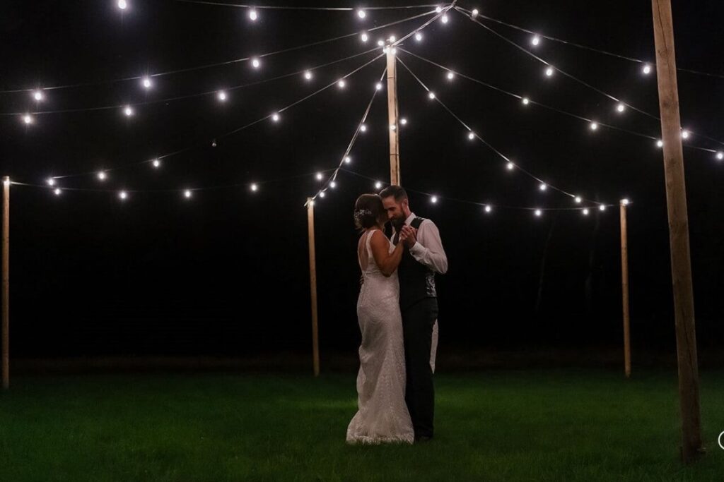 Laatste dans op trouwfeest: de bruid en bruidegom dansen een intieme laatste dans in de met lampjes verlichte tuin. 