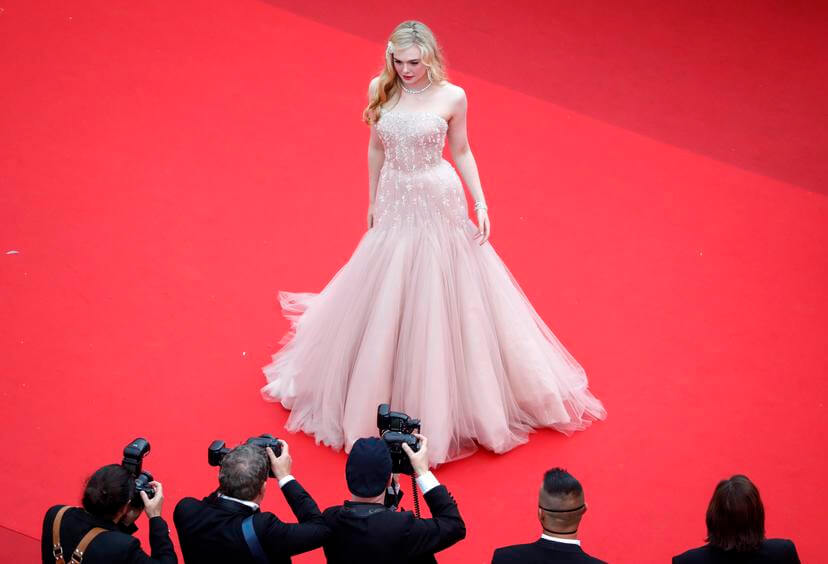 Blonde dame draagt een lichtroze, lange strapless trouwjurk op de rode loper in Cannes tijdens de editie van 2022. 
