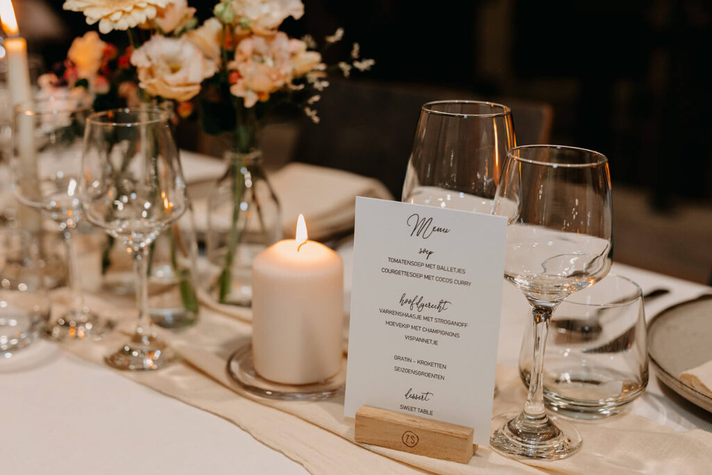Trendy huwelijksvideo waarop een prachtige tafel met ecrukleurig tafelinnen, bloemen en kaarslicht en een menu op geschikt staan. 