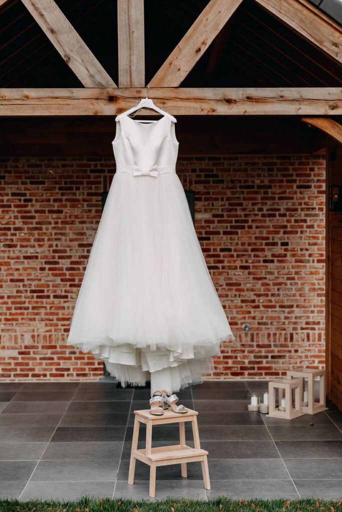 Trendy huwelijksvideo waarbij een lange witte bruidsjurk met een strikje in de taille ophangt aan een houten balk. 