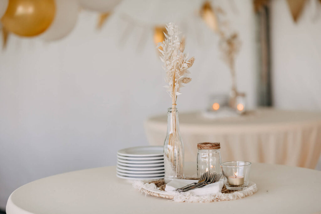 Een prachtige feesttafel kan je zelf aankleden als je goedkoper wil trouwen. Beige tafellinnen en servies en bloemendecoraties van pampasgrassen. 