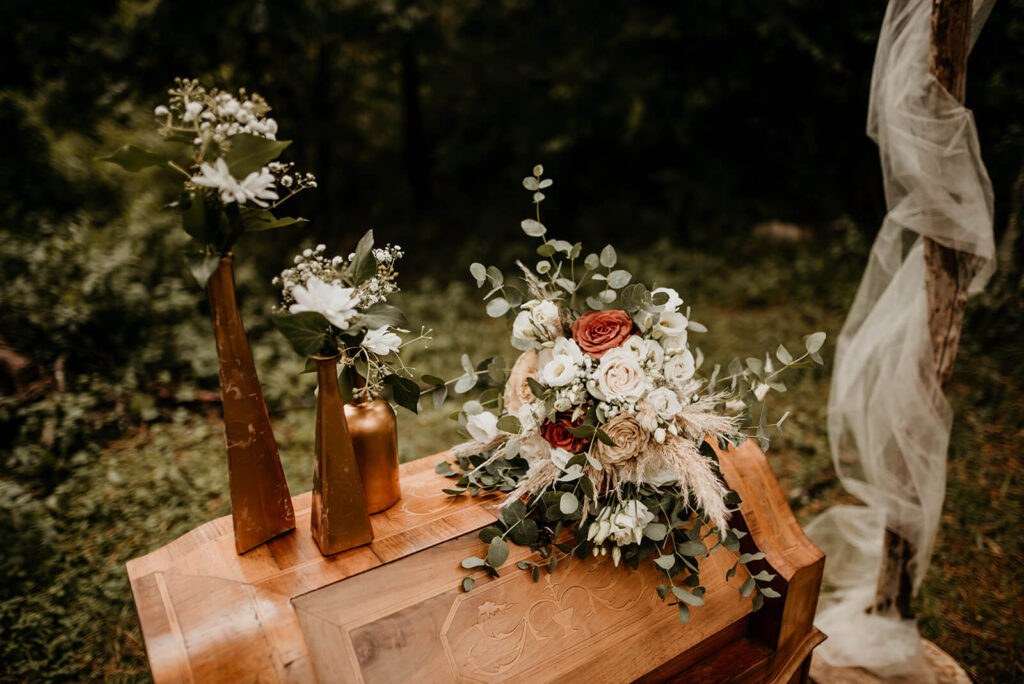 Trouwen in het bos tijdens een persoonlijke huwelijksceremonie met decoratie en bloemen in bostinten. 