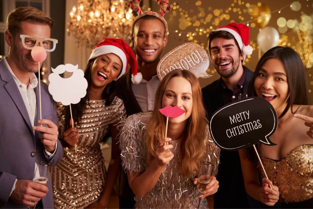 Joyful colleagues wearing a gold sequin dresses and a Christmas gadgets at a holiday party. 