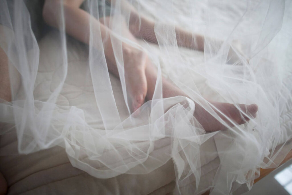 De ideale huwelijksreis waarbij een kersvers bruidspaar op bed ligt onder een muskietennet. 