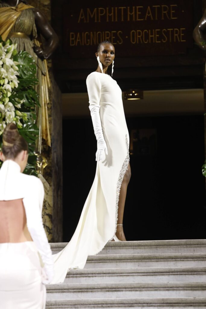 De grootste trends van Paris Haute Couture Week waarbij een model een witte jurk met hoge beensplit afgezet met briljantjes draagt. 