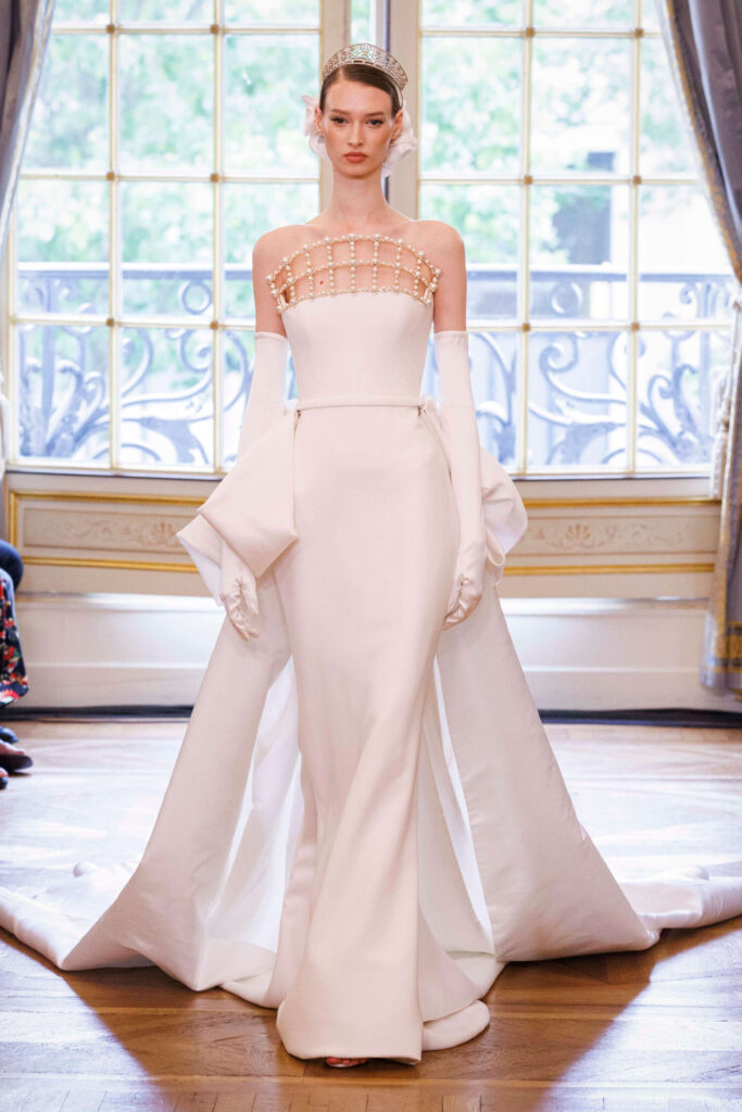 De grootste trends van Paris Haute Couture Week waarbij een model een witte trouwjurk draagt met lange witte handschoenen. 
