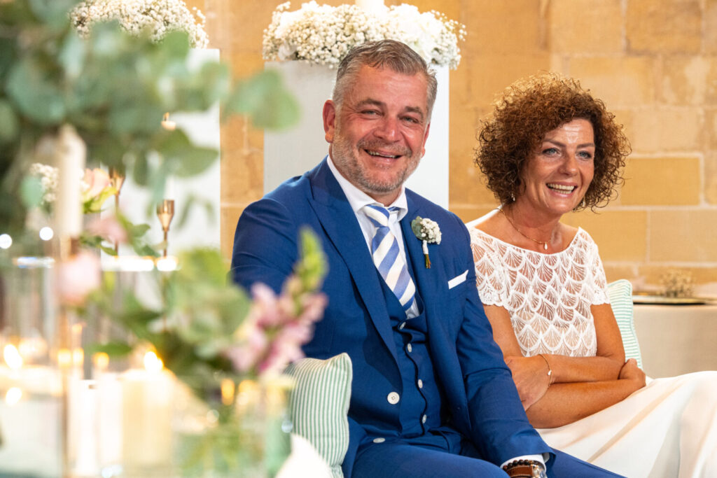 Trouwceremonie en trouwfeest in de kerk: bruid en bruidegom zitten naast elkaar en lachen 