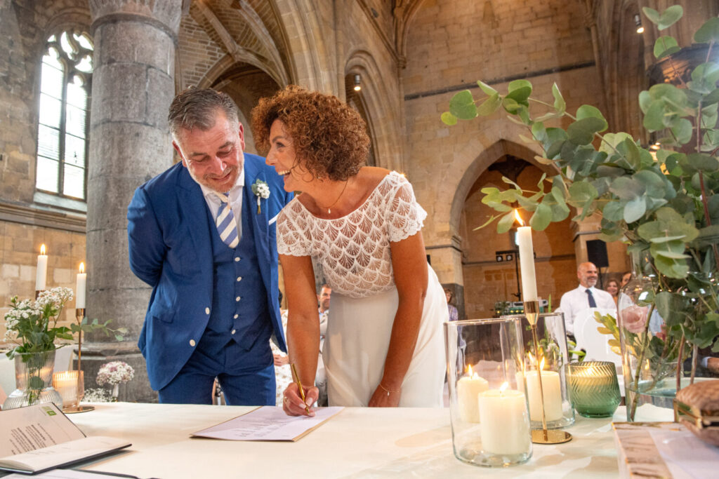 Trouwceremonie en trouwfeest in de kerk: bruid en bruidegom staan naast elkaar en tekenen het huwelijksregister. 